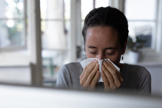 Woman blowing her nose at home