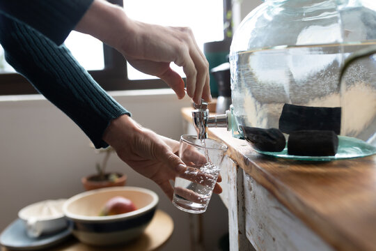 Mid section of woman pouring water in a glass at home