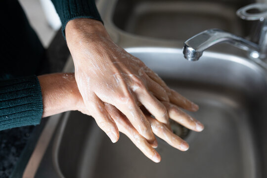 Mid section of woman washing her hands in the sink