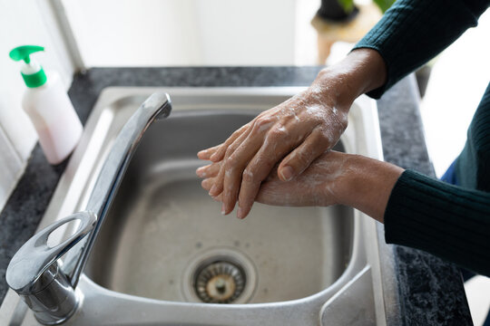 Mid section of woman washing her hands in the sink