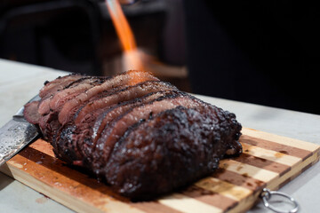 Grilled beef steak cut on a wooden board -meat flamed with torch - homemade barbecue - cooking meat on the grill