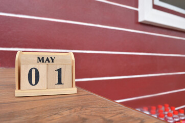 May 1, Number cube with wooden table beside the wall.