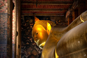 Fototapeta premium Face of Golden Reclining Buddha Statue at Wat Pho Temple, Bangkok, Thailand