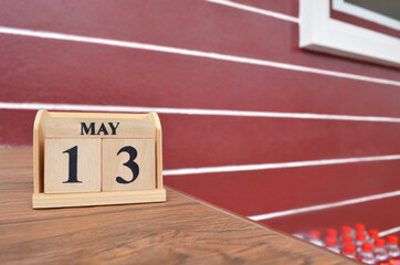 May 13, Number cube with wooden table beside the wall.