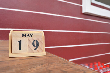 May 19, Number cube with wooden table beside the wall.