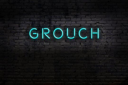 Neon sign. Word grouch against brick wall. Night view