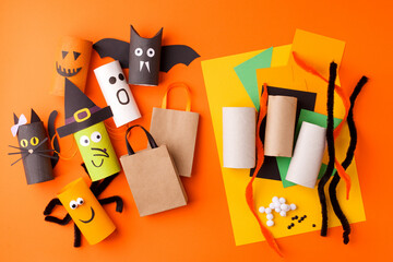 Child creates decorations for Halloween party from toilet roll. Easy eco-friendly DIY master class, craft for kids. Materials for creativity, recycle reuse concept of holiday art activities