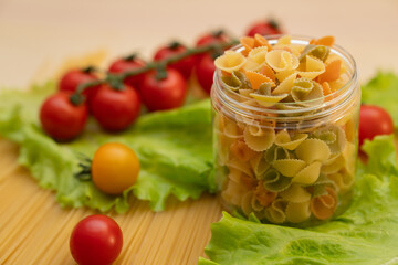 Pasta with vegetables in a plate.  Ingredients for cooking Italian Pasta. Tomatoes, cherry greens. Background from spaghetti.