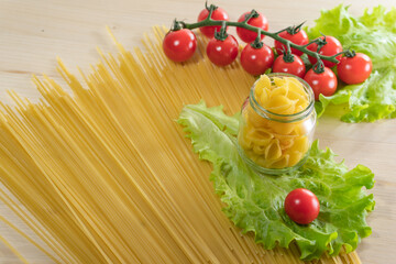 Background from spaghetti. Frame for the recipe of products. View from above. Ingredients for Italian pasta tomatoes, cherry greens.