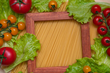 Background from spaghetti. Frame for the recipe of products. View from above. Ingredients for Italian pasta tomatoes, cherry greens.