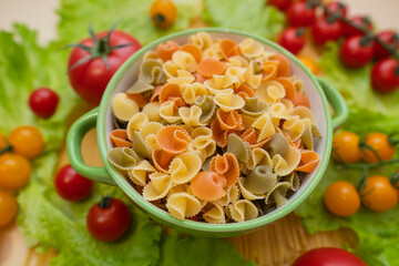 Pasta with vegetables in a plate.  Ingredients for cooking Italian Pasta. Tomatoes, cherry greens. Background from spaghetti.