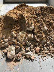 Gravel stones or rocks and brown dirt in a container, view from above