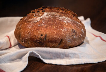 Baked loaf of artisanal whole wheat rustic sourdough bread with black olives