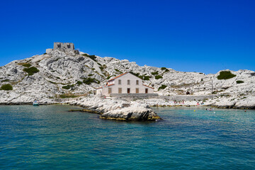 Fototapeta na wymiar Ile du Frioul à Marseille par temps calme, mer bleue, ciel bleu, crique avec élevage de poissons. Photo prise d'un bateau au mouillage