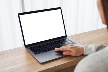 Mockup image of a woman using and touching on laptop computer touchpad with blank white desktop screen on wooden table