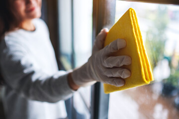 A young woman wearing protective glove cleaning the window for housework concept