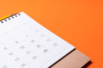 close up of calendar on the orange table background, planning for business meeting or travel planning concept