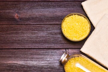 Bath salt and beige towels on a wooden background. place for text, top view.