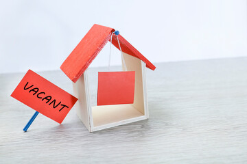 A toy house with hanging signage and vacant message on a placard  