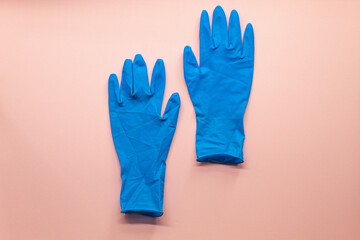 Two blue cleaning gloves on a pink background