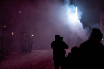 Fototapeta premium People watch the launch of small fireworks in the winter on the street. New year and Christmas celebrations in Russia. Traditions of digging and setting off fireworks.