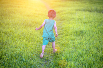 A two-year-old boy in a green vest is playing