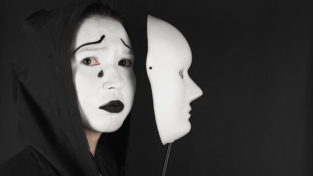 Theatrical cosmetics sad mask. The girl hides emotions behind a mask.
