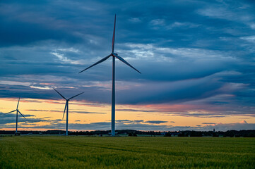 Fototapeta na wymiar big windmills on field with dramatic sky