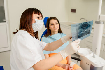 Young woman dentist explaining to her patient on a dental x-ray panoramic radiography all the dental treatment that needs to do in dentistry