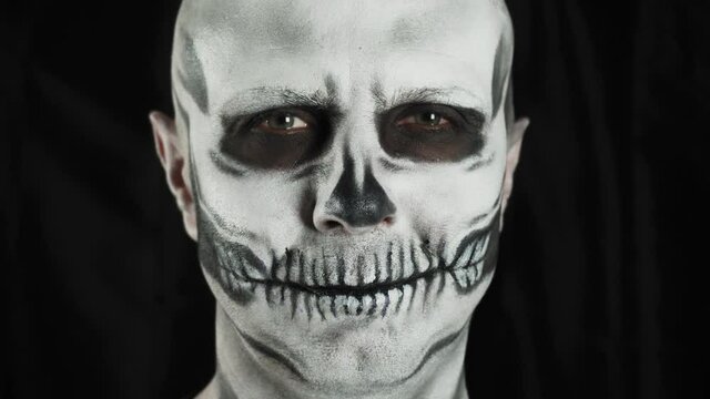 Makeup skeleton for Halloween. Human skeleton on a dark background. A man is looking at the camera.