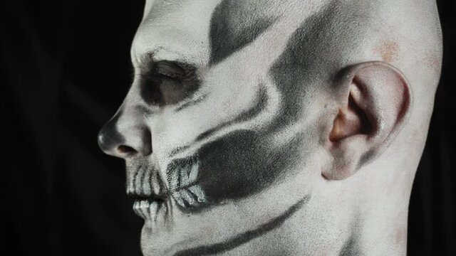 Makeup skeleton for Halloween. Human skeleton on a dark background. Man looks away