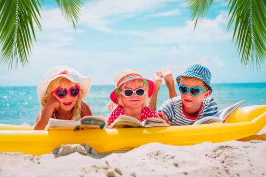 cute boy and girls read books on beach, family vacation