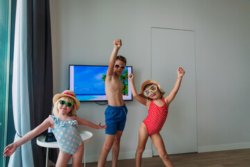 Summer at home, kids in swimsuits and glasses with sea on TV screen