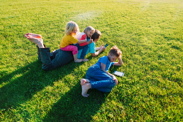 father and kids relax on summer green grass, family reading in nature