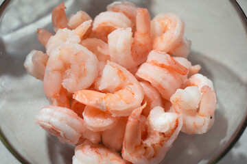 Fresh raw shrimp in a bowl on a white table - skinless shrimp
