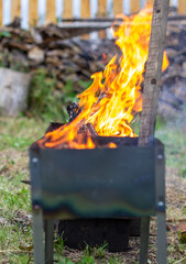 A fire is burning in a metal grill. A large, bright flame of fire at close range. Outdoor recreation.