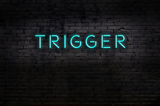 Neon sign. Word trigger against brick wall. Night view