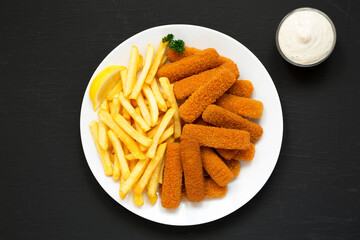 Homemade Fish Sticks and Fries with Tartar Sauce on a black background, top view. Flat lay, overhead, from above.