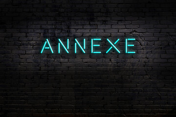 Night view of neon sign on brick wall with inscription annexe