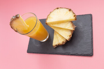 glass with pineapple juice and slices of fresh pineapple fruit