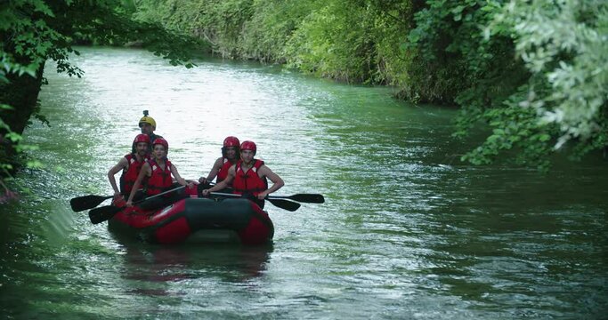 Group of people on raft boat doing rafting on whitewater river during sunset or sunrise. Warm back light. Friends italian trip in Umbria.4k slow motion