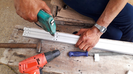 man at work drilling in aluminium frame and making home interiors in workshop