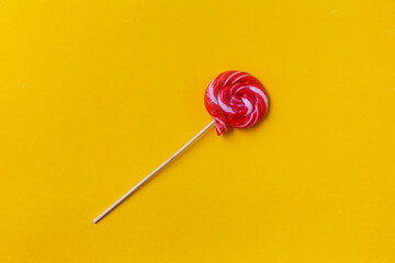 Сolorful lollipop on a yellow background. Delicious round candy