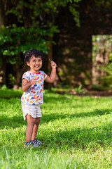 Naklejka premium Playful Pretty Indian girl child/infant playing outdoors with nice environmental background
