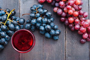 glass of red wine and grapes on black wooden table background