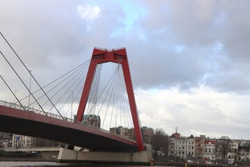 Fototapeta premium Red steel bridge over river Nieuwe Maas named Willemsbrug in Rotterdam.