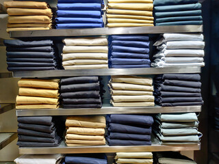Large assortment of jeans trousers arranged on the shelf of a clothing store