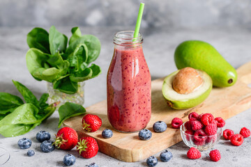 Healthy vegetarian smoothie made from fresh berries, avocado and spinach in a bottle. Selective focus