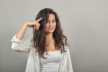 Fototapeta premium Confused portrait surprised young, twisting index finger at temple, asking to think carefully, saying what crazy idea. You an idiot. Kidding me. Pointing head with hand, thinking, focused on task.