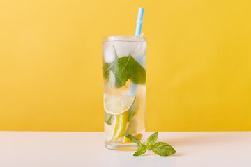 Glass with iced tea with lemon slices, mint and ice cubes, non alcoholic cocktail with drinking...